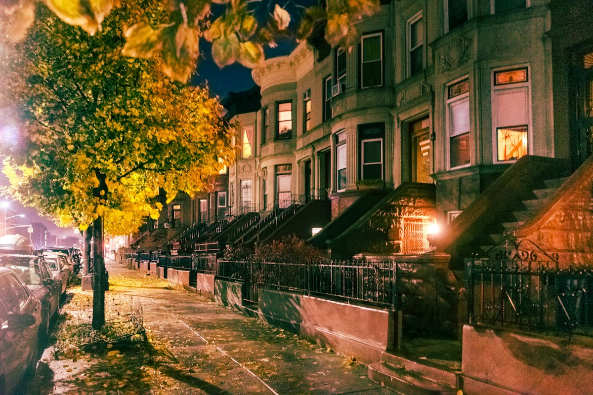 A row of brownstones at night with lit windows